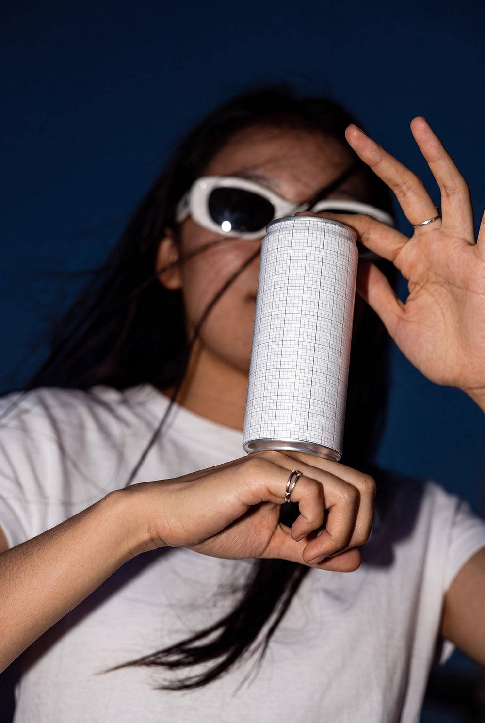 Modern beverage packaging mockup with a hand-held can and editorial flash lighting.