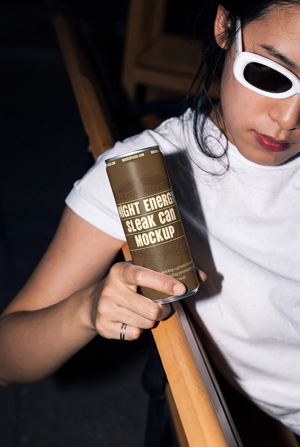 Aluminum drink can mockup held by a model wearing sunglasses and a white shirt.