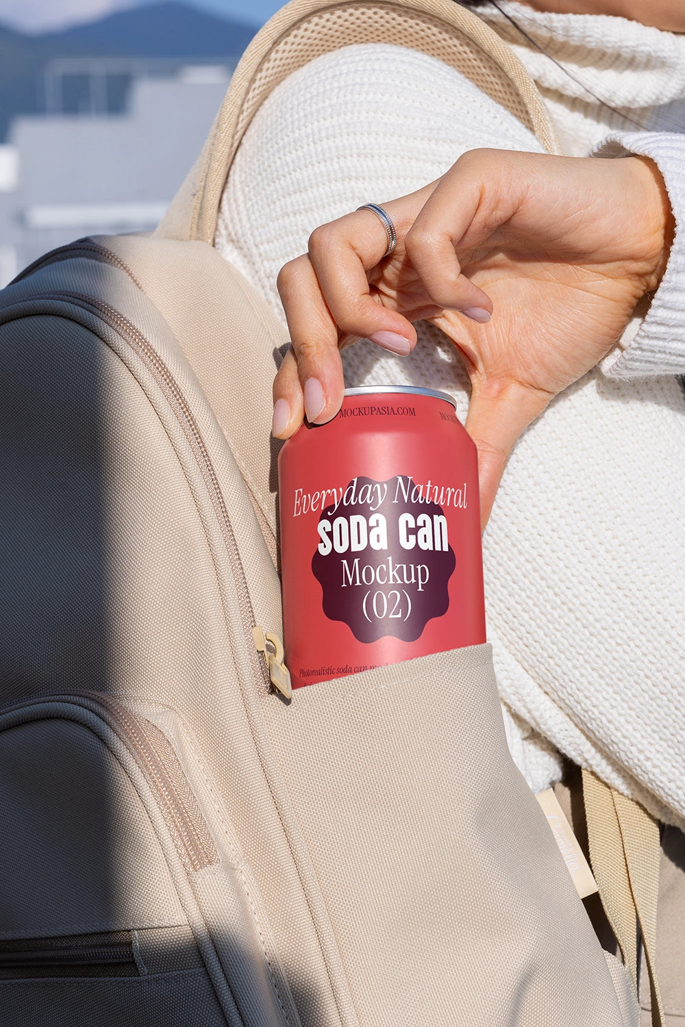 Hand holding soda can mockup from backpack pocket outdoor lifestyle beverage packaging scene