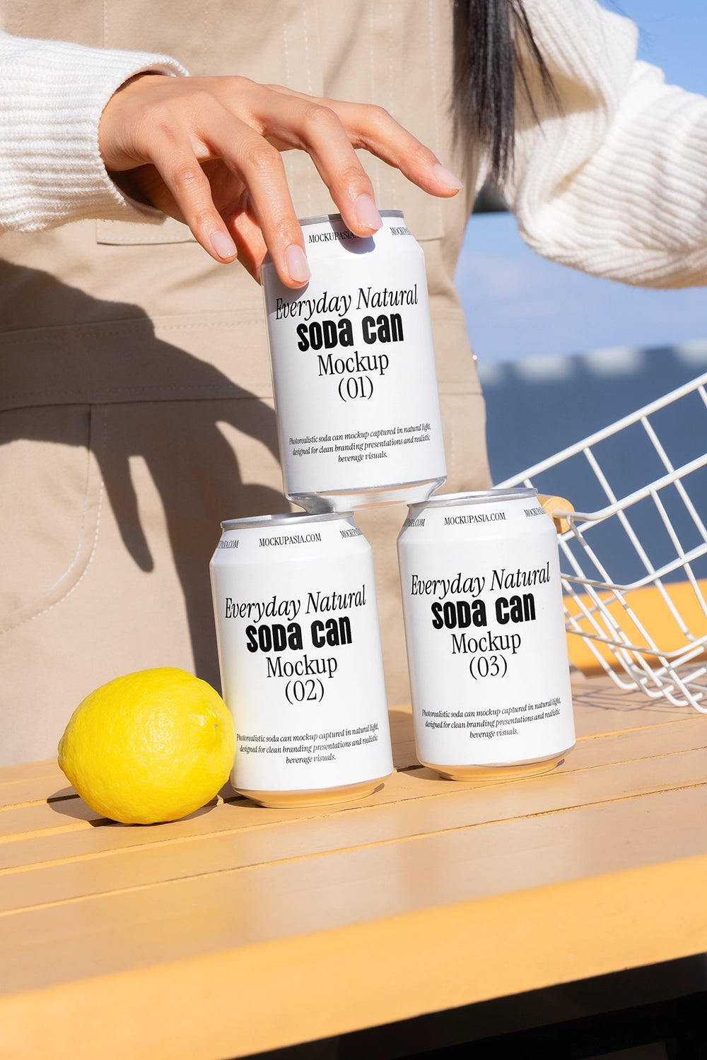 Soda cans mockup with hand stacking and lemon outdoor lifestyle aluminum beverage packaging scene
