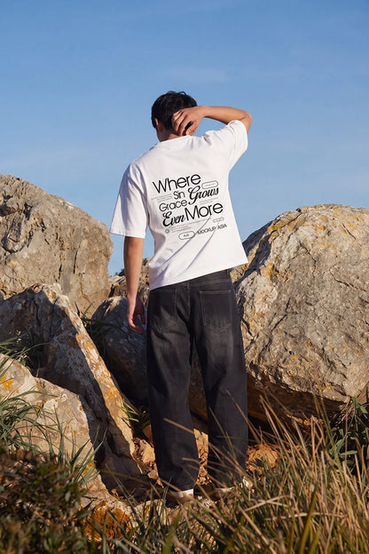 White T-shirt mockup AUG04 – Back View, Hand Raised, outdoor rocky hillside – Mockup.Asia