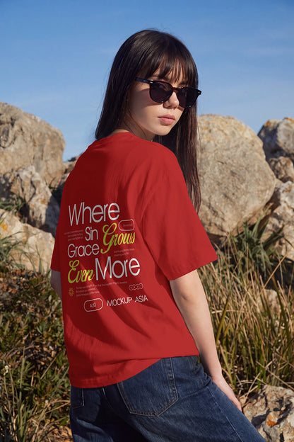 Three-quarter back view of a woman wearing a custom graphic T-shirt surrounded by natural rocks and vegetation.