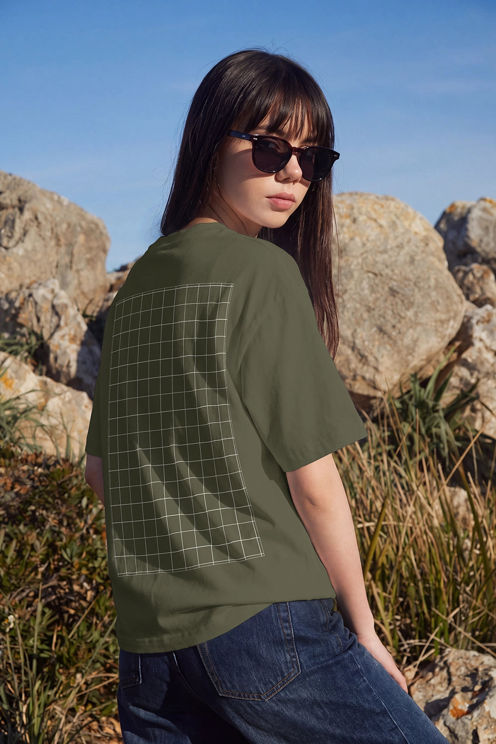 White oversized T-shirt mockup with realistic fabric folds and an editable back design area under natural sunlight.