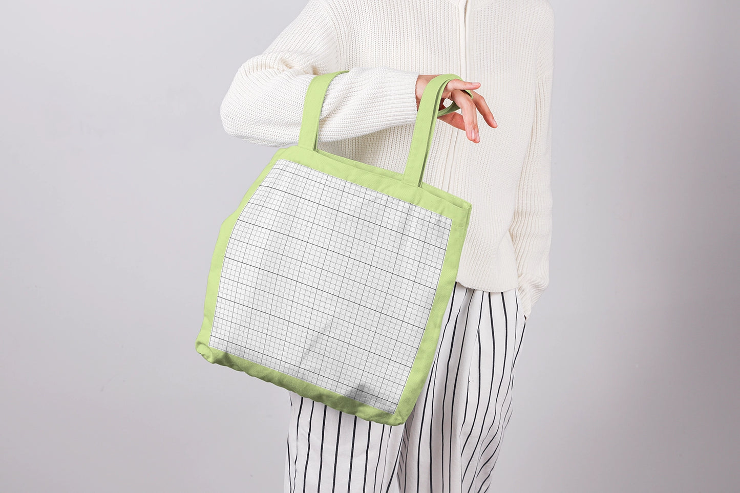 eco tote bag mockup in hand with neutral outfit and soft lighting setup