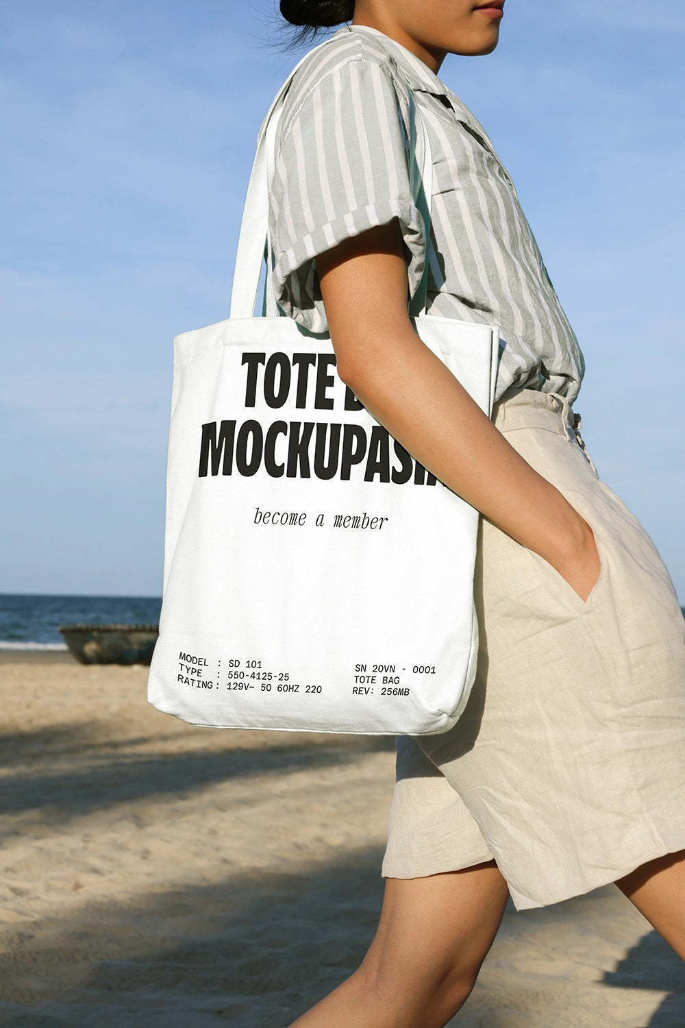tote bag mockup carried on shoulder at beach with natural sunlight and ocean background