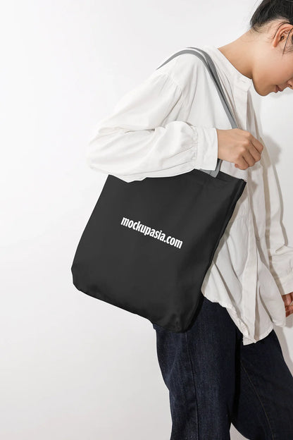 black canvas tote bag mockup on shoulder with clean studio background, minimal lifestyle scene
