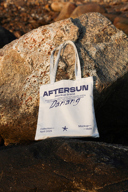 canvas tote bag mockup on rocks with sunset lighting, outdoor beach lifestyle scene