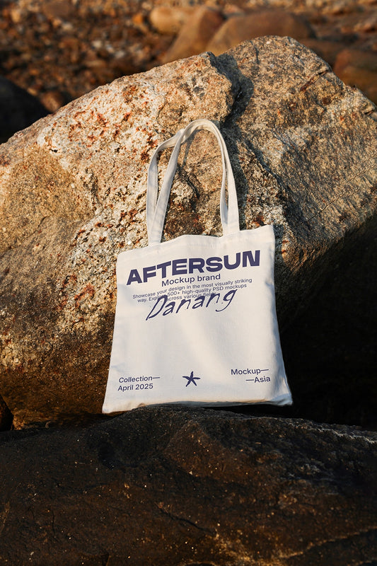 canvas tote bag mockup on rocks with sunset lighting, outdoor beach lifestyle scene
