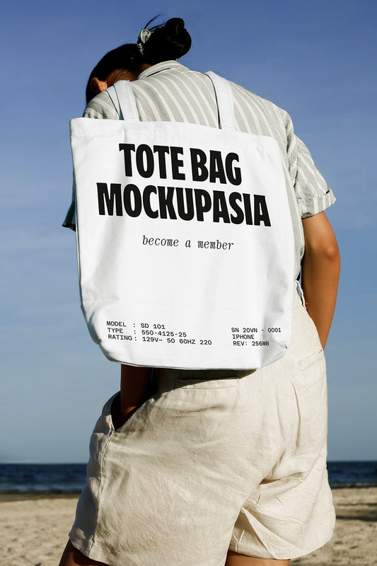 tote bag mockup worn on shoulder at beach with clear sky and lifestyle setting