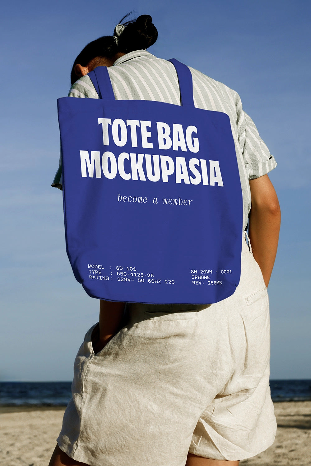realistic canvas tote bag mockup on person back with seaside background and natural light