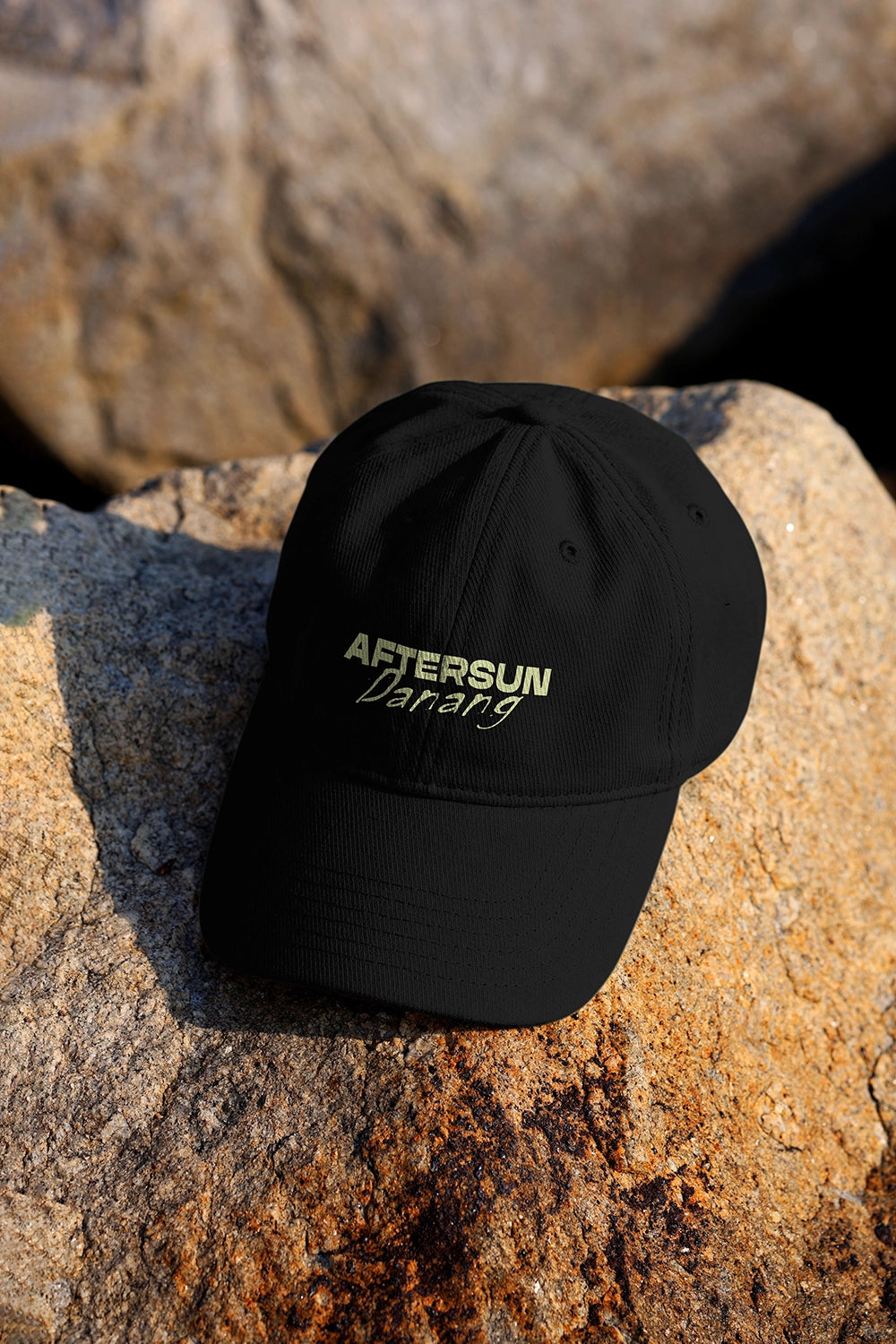 minimal hat mockup on rocky surface with warm lighting and clean branding presentation
