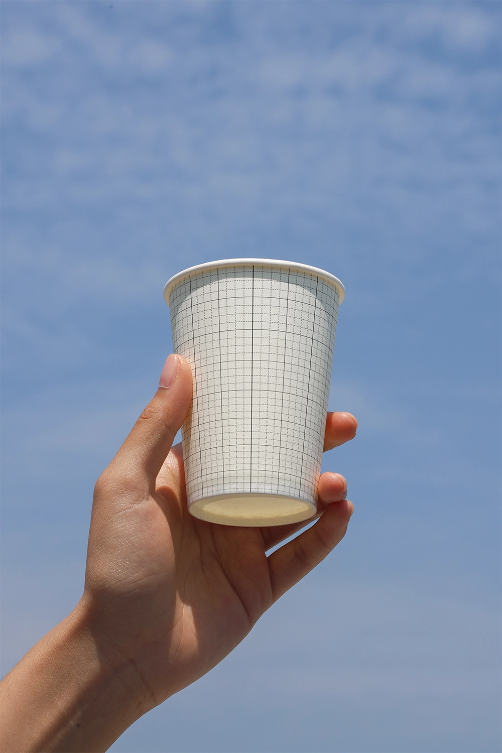 minimal paper cup mockup with hand holding cup outdoor sky backdrop branding presentation