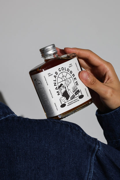 Tilted cold brew bottle mockup held in hand with clean studio background
