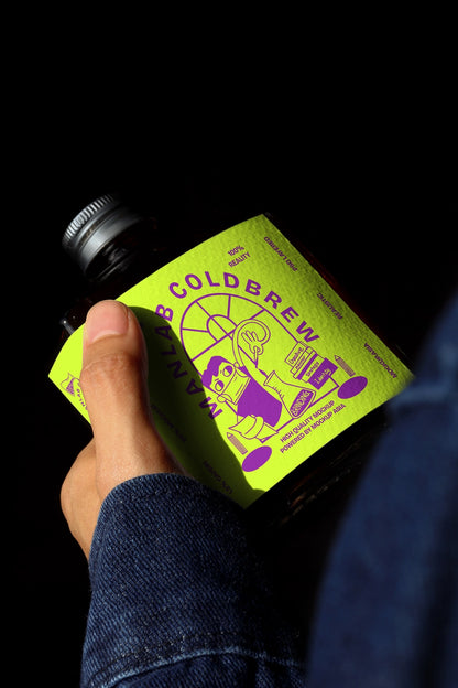 Dark cold brew bottle mockup held in hand with dramatic lighting and deep shadows
