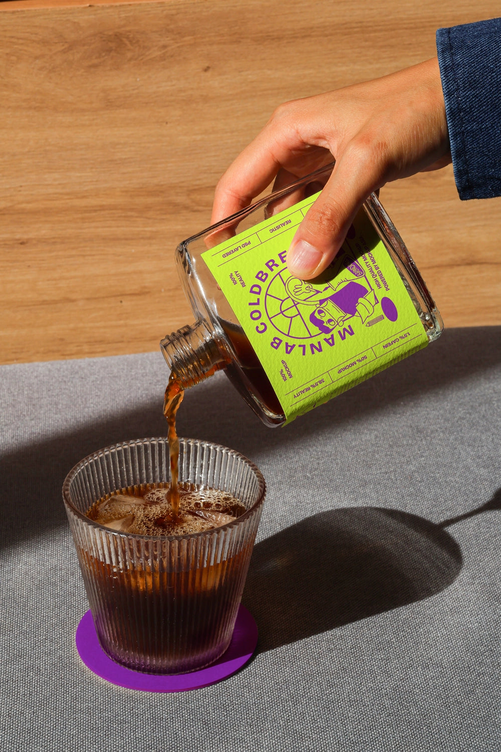 Pouring cold brew bottle mockup into glass with realistic coffee flow and shadow

