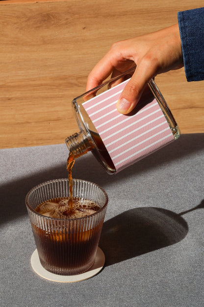 Iced coffee bottle mockup with pouring action and natural lighting setup
