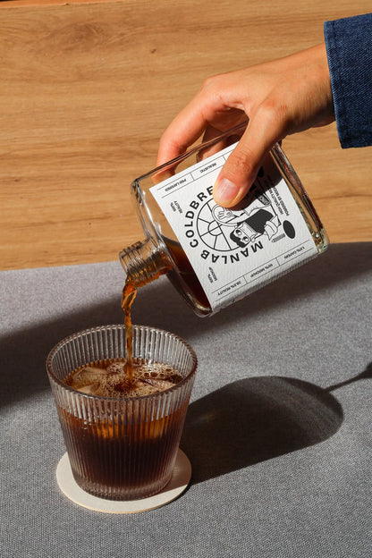 Pouring cold brew bottle mockup into glass with realistic coffee flow and shadow