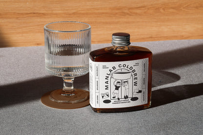 Cold brew bottle mockup with glass in clean lighting and realistic shadow setup
