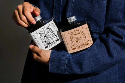 Cold brew coffee bottle mockup with two bottles in handheld composition
