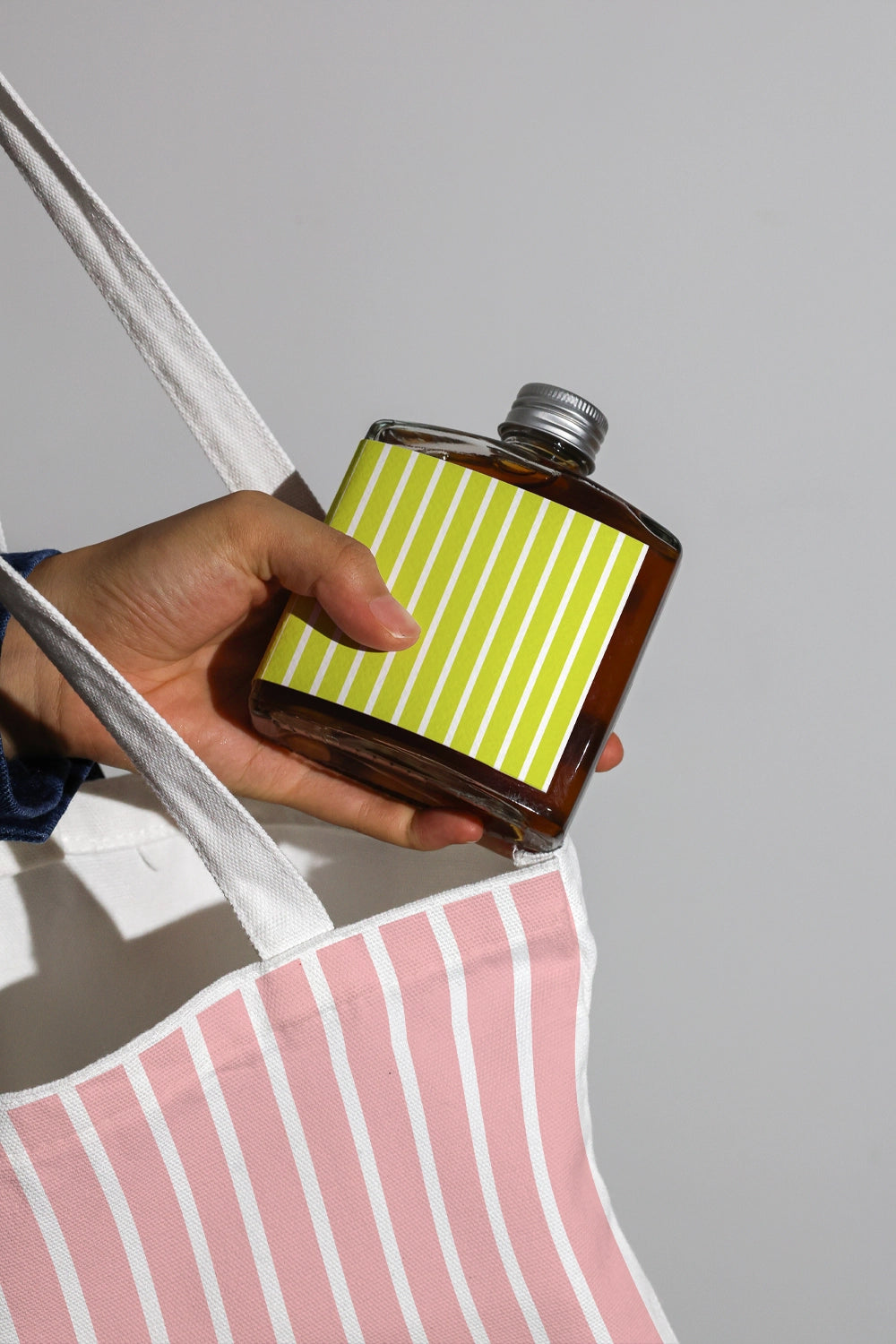 Cold brew bottle mockup held with tote bag in lifestyle scene

