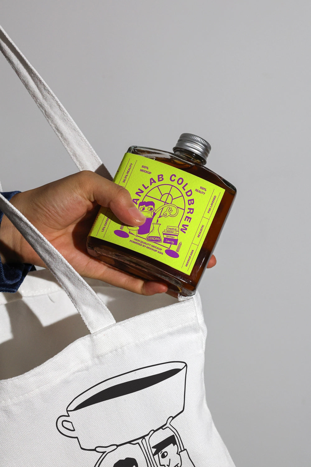 Cold brew drink bottle mockup with hand and fabric tote bag context
