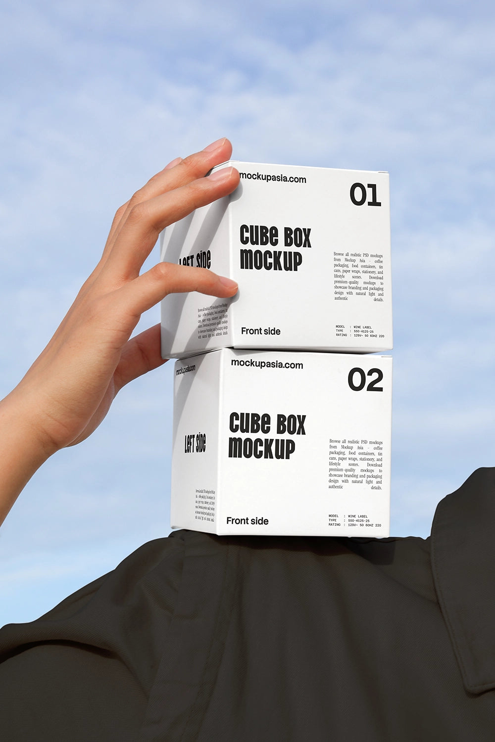 Cube box mockup with two stacked packaging boxes held by hand against sky background