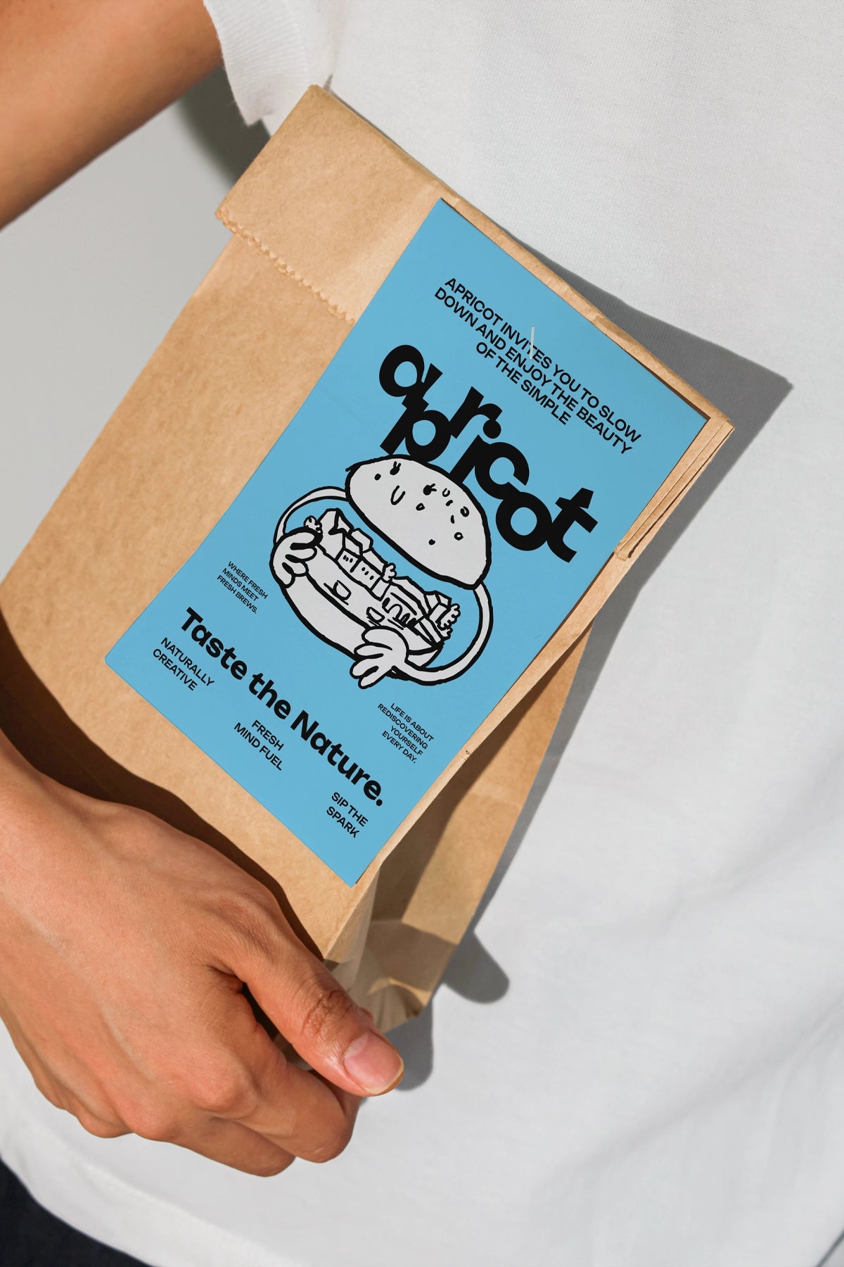 kraft pouch mockup with blank grid label in hand, natural light and shadow aesthetic