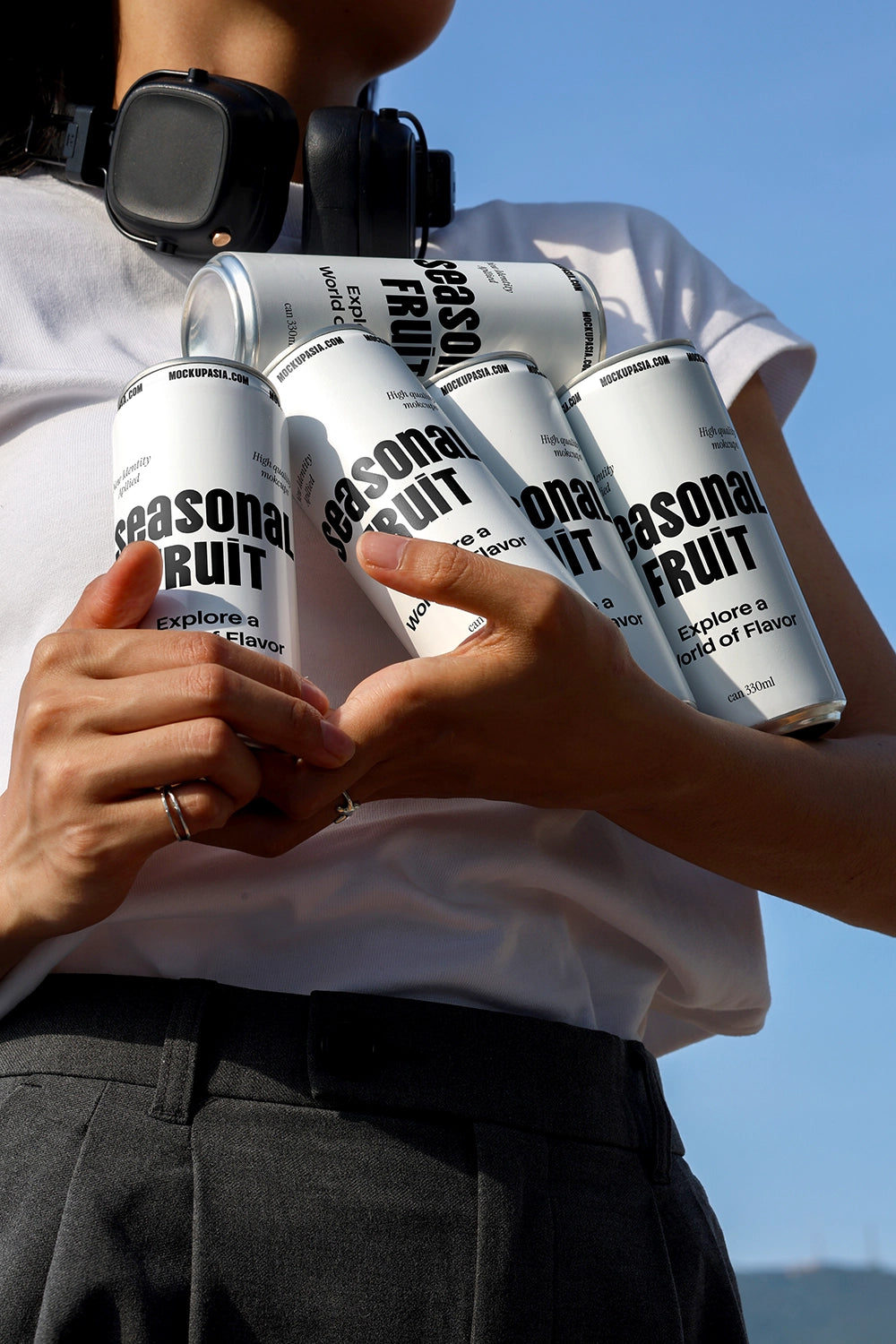 Multiple soda cans mockup held in hands with lifestyle composition and blue sky background