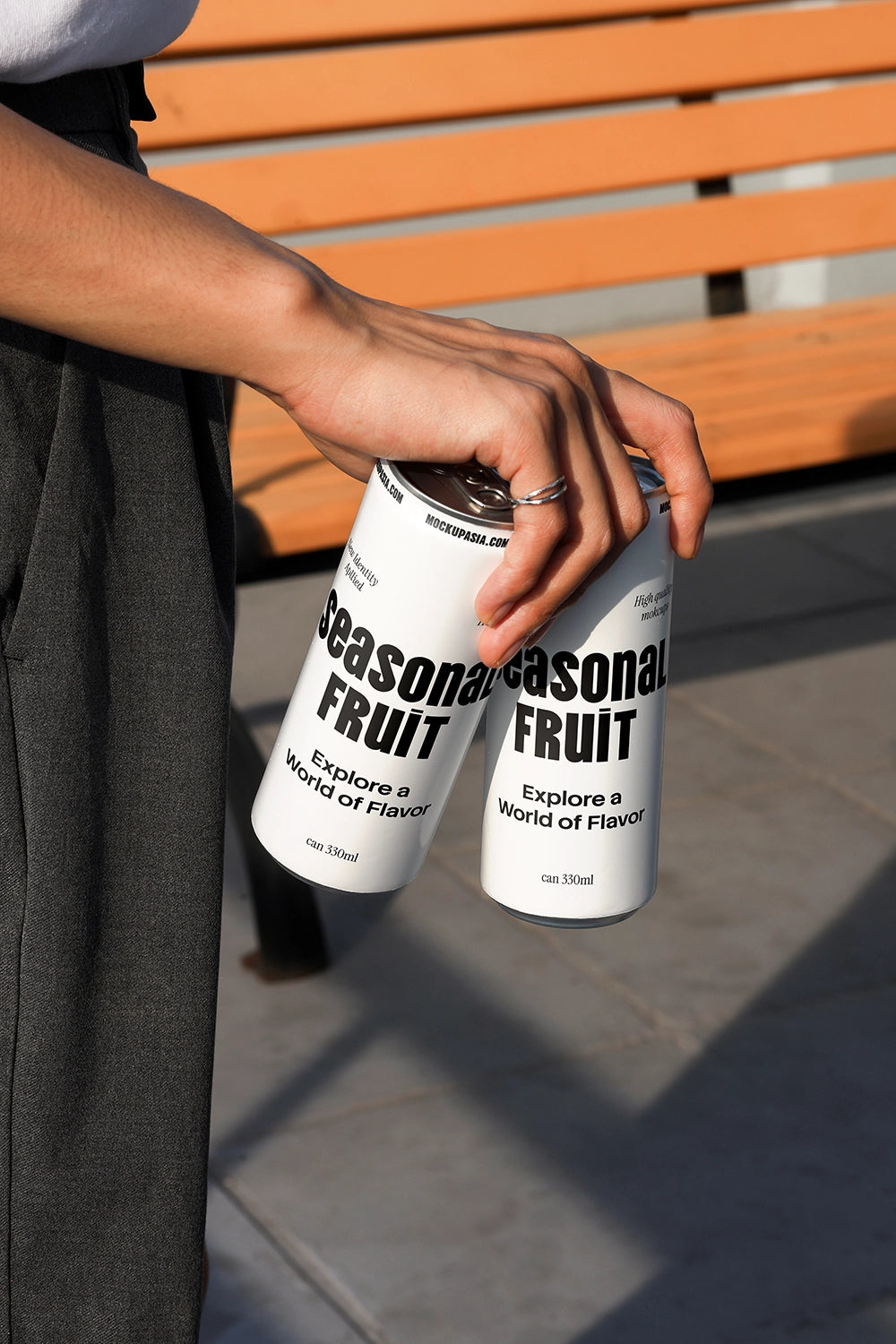 Dual soda can mockup held in hand outdoors with natural sunlight and lifestyle setting