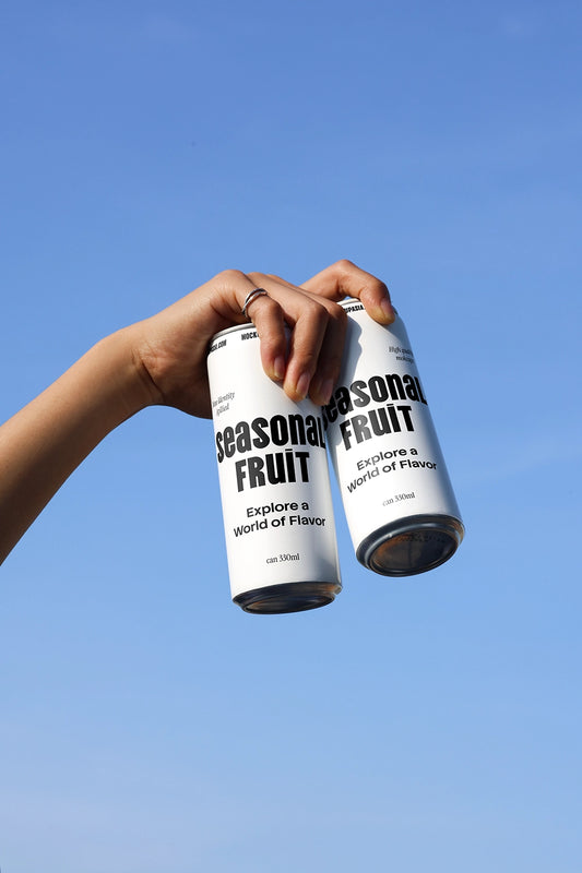 Dual soda can mockup held by hand against blue sky showing beverage packaging variations