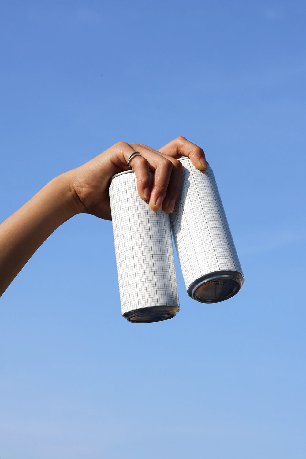 Minimal dual soda can mockup with natural lighting and sky background for beverage design showcase