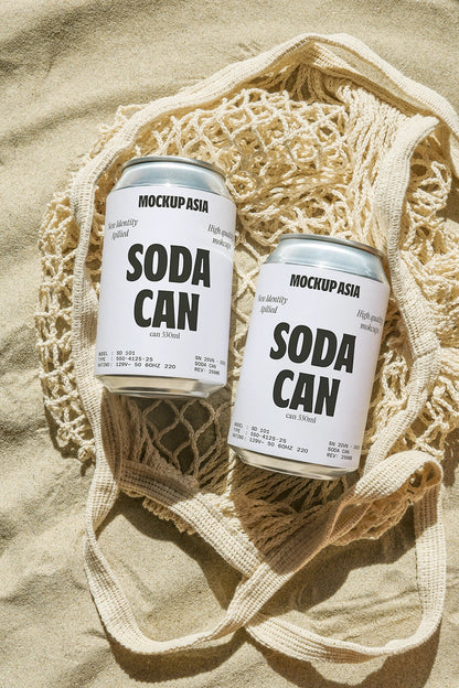 Soda can mockup on sand inside woven bag with natural beach lighting and summer lifestyle scene